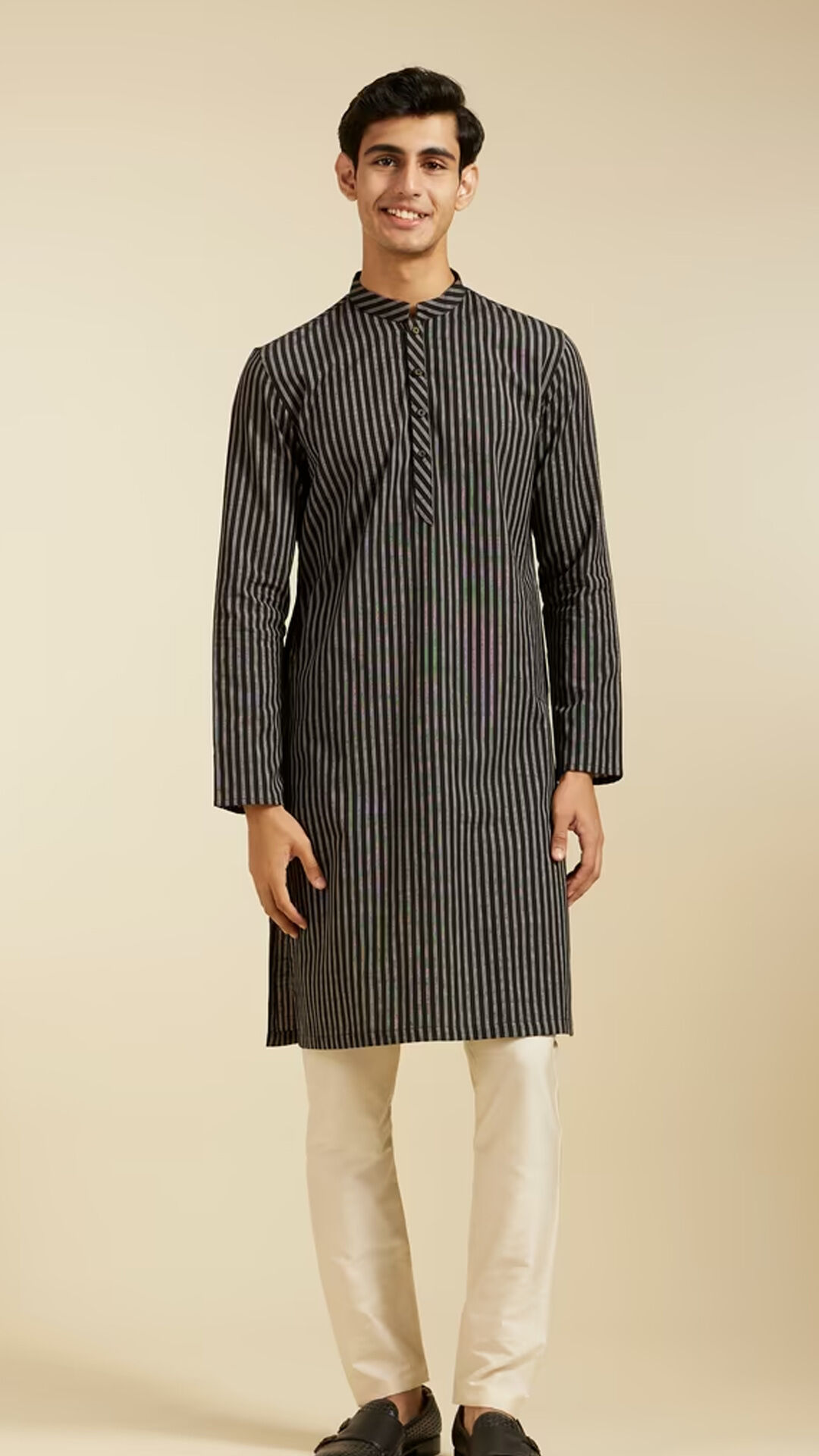 Man wearing a black and grey vertical striped kurta with a mandarin collar, paired with cream trousers for a modern yet traditional ethnic look.